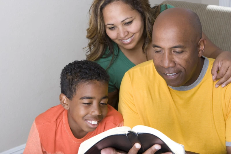 Husband and Father reading the Bible to his family.